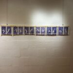 A series on monoprint images with deep blue background and white shiloette of figure moving through a gymnastics skill. The images are pegged to a wooden baton and hung against a white wall